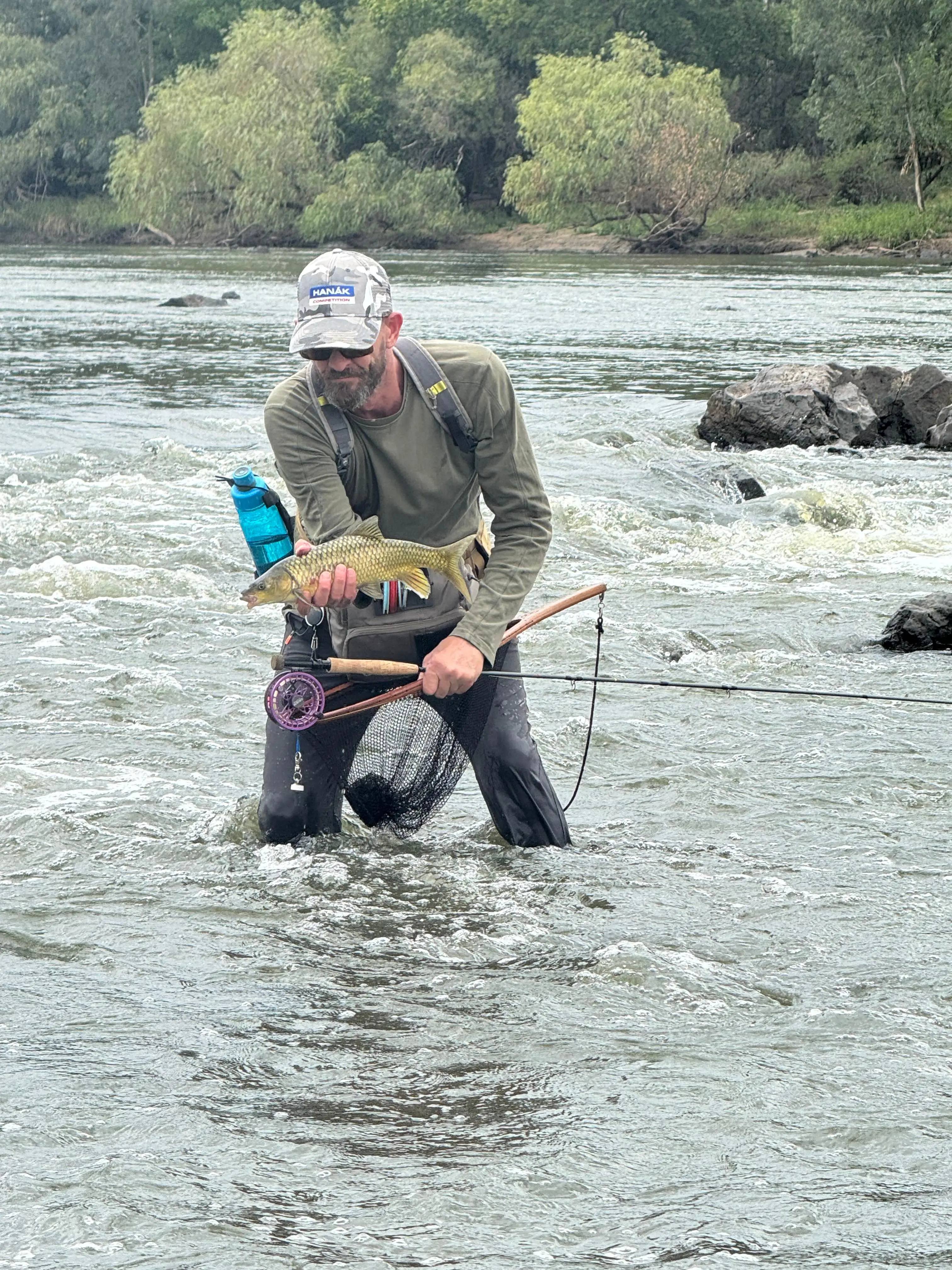 Shayne Prinsloo holding a Smallmouth Yellowfish while wading on the Vaal River